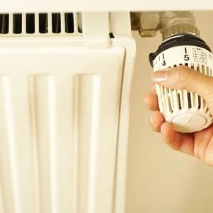 Hand draait aan de thermostaatknop van een radiator